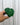 A hand holding a 2-inch pot of Anthurium 'Clarinervium' with heart-shaped leaves against a metal background.