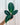 A hand holding a potted Calathea 'Jungle Velvet' plant with dark green leaves and hints of purple underneath, against a metal background.