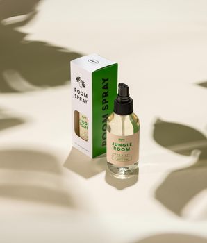 A room spray bottle with a black cap and a label that reads 'Jungle Room Spray'. The bottle is placed next to its packaging box with matching design and text.