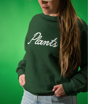 Person wearing a dark green sweatshirt with white 'Plants' text against a green background